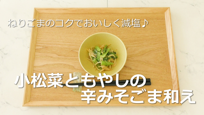 動画「お手軽野菜レシピ【小松菜ともやしの辛みそごま和え】」のサムネイル画像。完成した小松菜ともやしの辛みそごま和えがお盆に載っている。