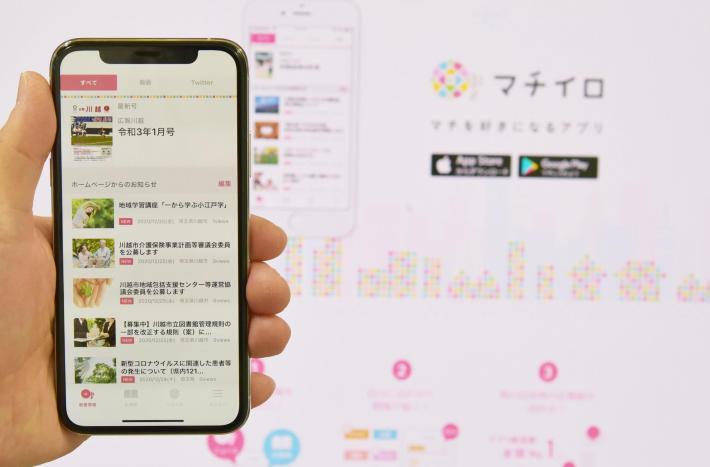 写真：マチイロのページを表示したスマホを手に持っている