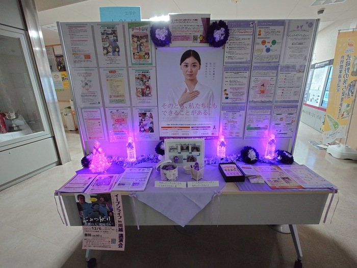 写真：本庁舎1階のパネル展示（パープルリボン）のパープル・ライトアップの様子