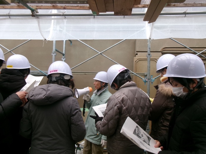 外壁を示しながら壁の構造を説明する職員とそれを聞く参加者の写真