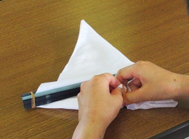 割り箸や輪ゴムを使ってハンカチを染める模様を作っている様子の写真