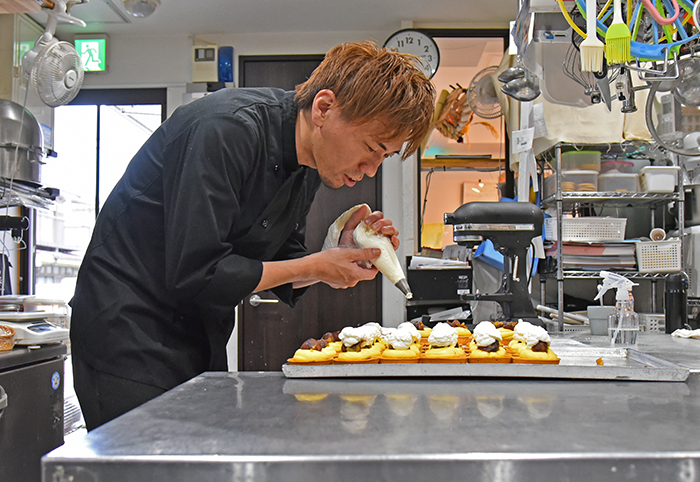 写真：店長の松本さんがケーキを作っている様子