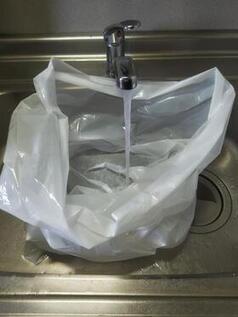 ゴミ袋に水道から水を入れている写真
