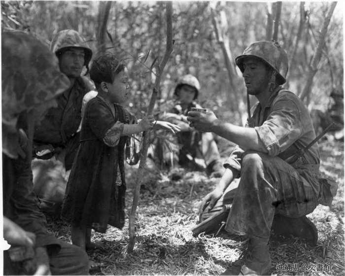 太平洋戦争当時の米軍のテニアン島上陸後、一人さまよっていたこどもに水を差し出すアメリカ兵の写真