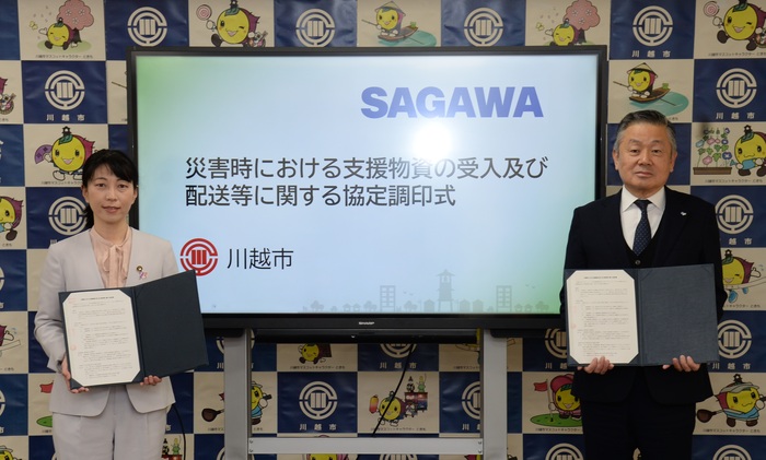 協定締結式の写真。モニターの前に、署名済みの協定書を持った川越市長と、佐川急便株式会社北関東支店支店長が並んだ記念写真。