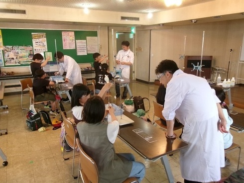 こどもたちと城西川越高校の教師と生徒が理科の実験をしている写真