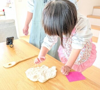 女の子がパン生地を手で伸ばしている写真